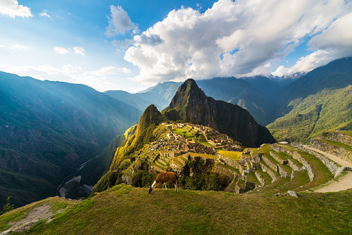 Machu Picchu iluminado por la luz cálida del atardecer. Gran angular vista desde las terrazas por encima con el cielo escénico y ráfaga de sol. Destino de viaje onírico, maravilla del mundo. Región Cusco, Perú. photo