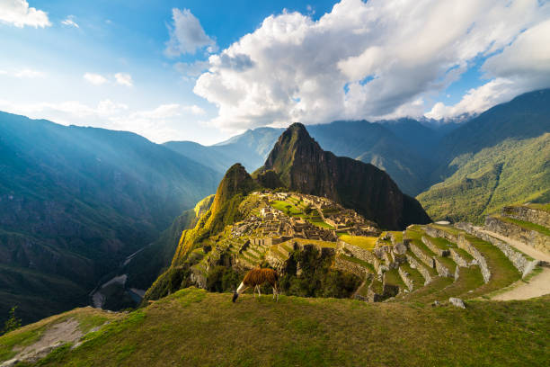 machu picchu, iluminado pela luz do sol quente. vista de grande angular a partir dos terraços acima com céu cênico e explosão de sol. destino de viagem onírica, maravilha do mundo. região de cusco, peru. - os andes - fotografias e filmes do acervo