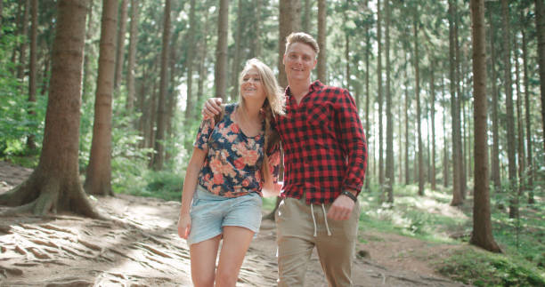 istock Smiling couple looking at camera while relaxing in woods. 858378112
