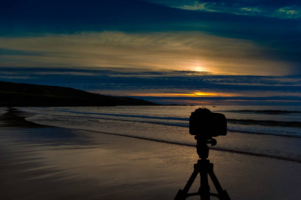 istock Camera on tripod with ocean and sunset in background 858387388