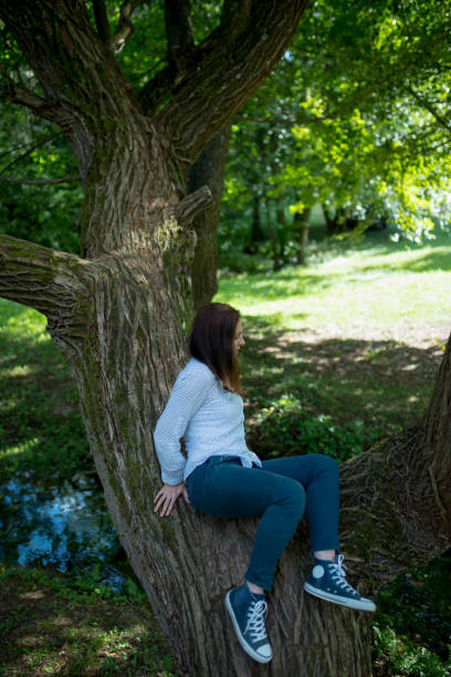 istock young girl is sitting on a tree 858388626