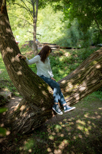 istock young girl is sitting on a tree 858392248