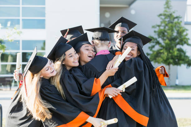 istock Multi-ethnic teenage graduates in cap and gown hugging 858448090