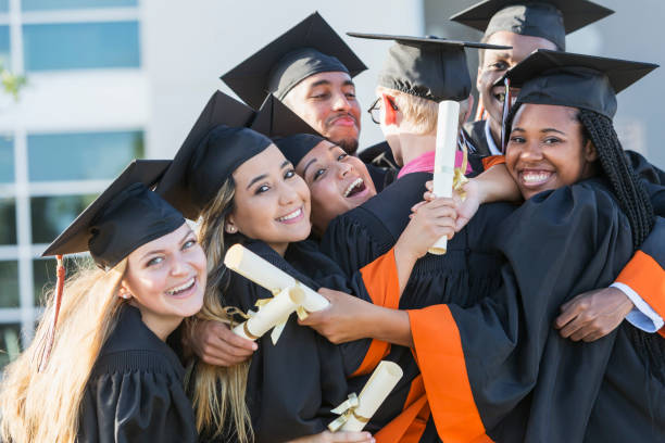 istock Multi-ethnic teenage graduates in cap and gown hugging 858448126