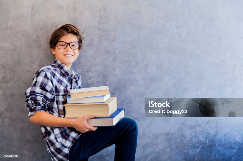 Cute teenage school boy holding books Cute teenage school boy holding books against wall Book Stock Photo