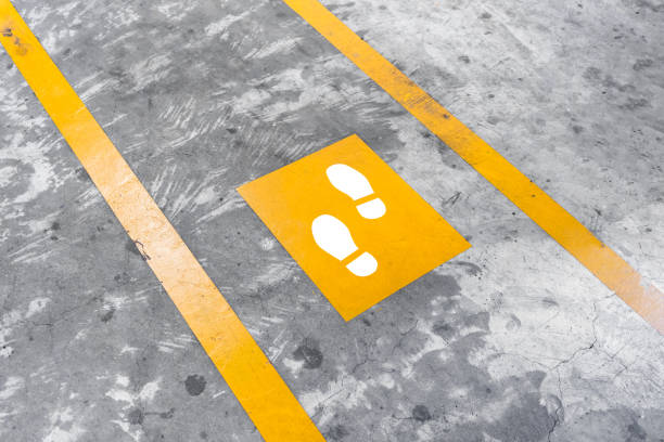 istock Walkway lane in parking building. Painted yellow footsteps between parallel yellow lines on abstract cement floor. 858451852