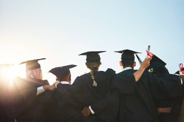 Only hard work gets you here Rearview shot of a group of university students standing outside on graduation day graduation clothing stock pictures, royalty-free photos & images