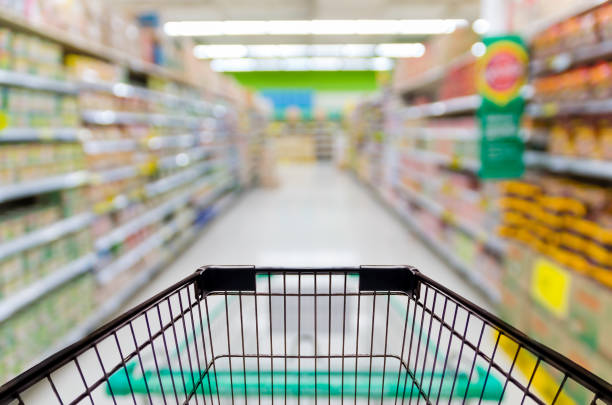 Female hand holding mobile smart phone on Supermarket blur background, business concept Female hand holding mobile smart phone on Supermarket blur background, business concept mark goodson screening room stock pictures, royalty-free photos & images