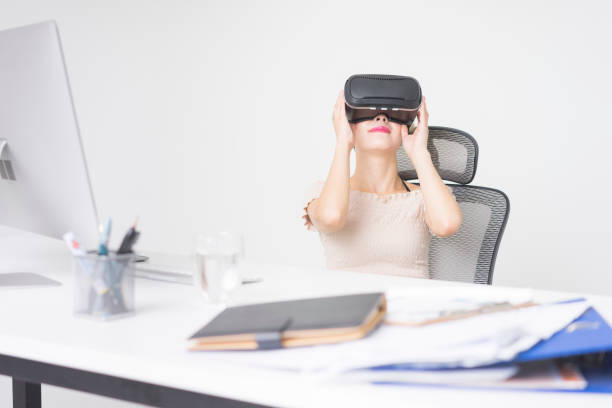 istock businesswoman wearing virtual reality simulator at office desk 858481654