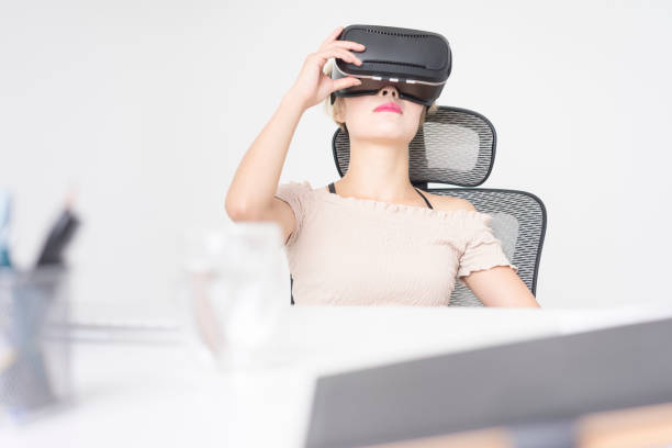 istock businesswoman wearing virtual reality simulator at office desk 858481670