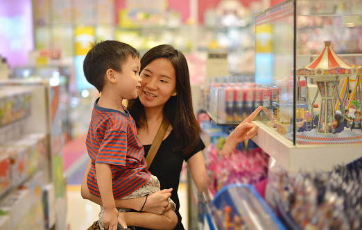 Young Asian mother and her kid shopping toy in shopping mall