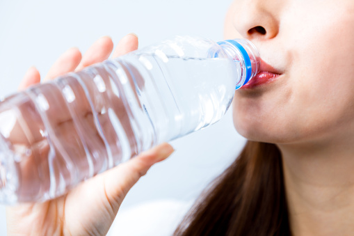concepto de hidratación. una mujer joven bebiendo una botella de agua. photo