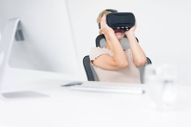 istock businesswoman wearing virtual reality simulator at office desk 858484902