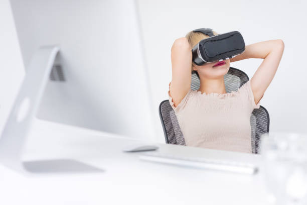istock businesswoman wearing virtual reality simulator at office desk 858484930