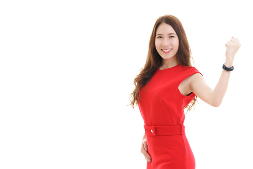 Beautiful young Asian woman in red casual dress smiling and raising her fist expressing successful in something isolated on white background