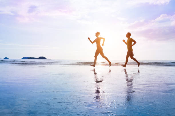 istock Young couple are jogging on beautiful sunset sea beach 858494236