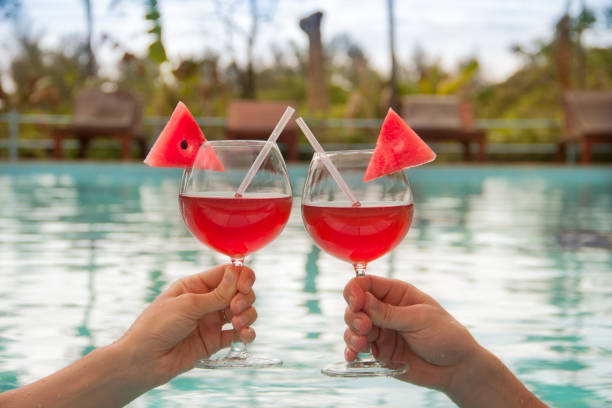 Two hands hold two clink glasses with red cocktail or juice stock photo
