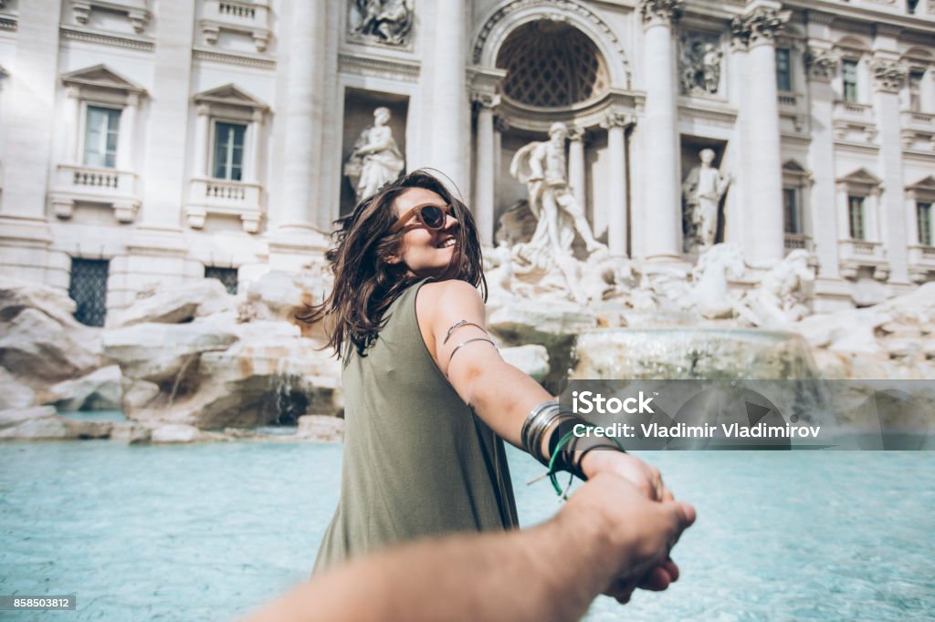 Young woman in front of Trevi fountain Young woman taking follow me picture in front of Trevi fountain in Rome Rome - Italy Stock Photo