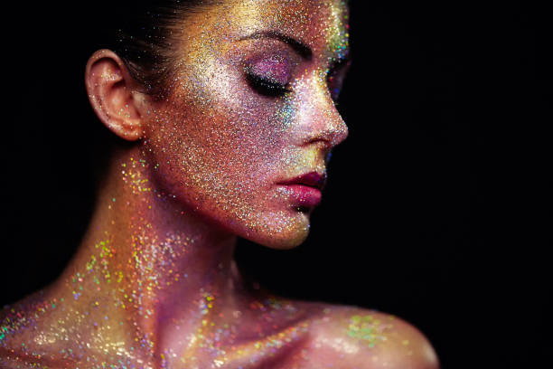 Portrait of beautiful woman with sparkles on her face Portrait of Beautiful Woman with Sparkles on her Face. Girl with Art Make-Up in Color Light. Fashion Model with Colorful Makeup body paint stock pictures, royalty-free photos & images