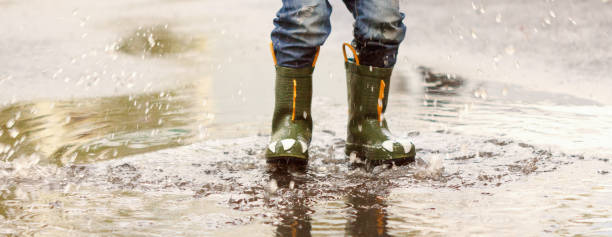istock child with rain boots jumps into a puddle 858515460