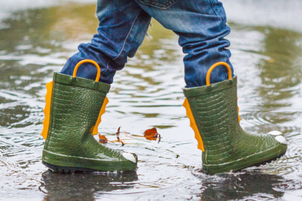 istock child with rain boots jumps into a puddle 858515504