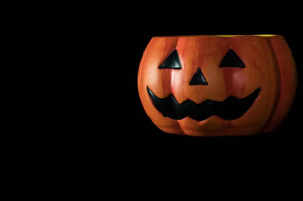 Photo of Halloween concept : Low key image of ceramic Halloween Pumpkin bucket isolated on black background
