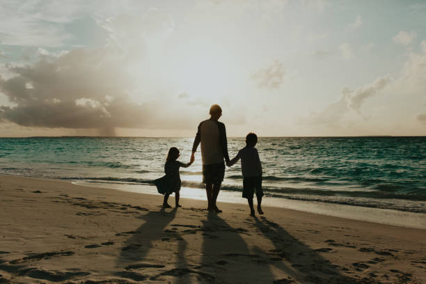 istock father with two kids walking on beach at sunset 858562174