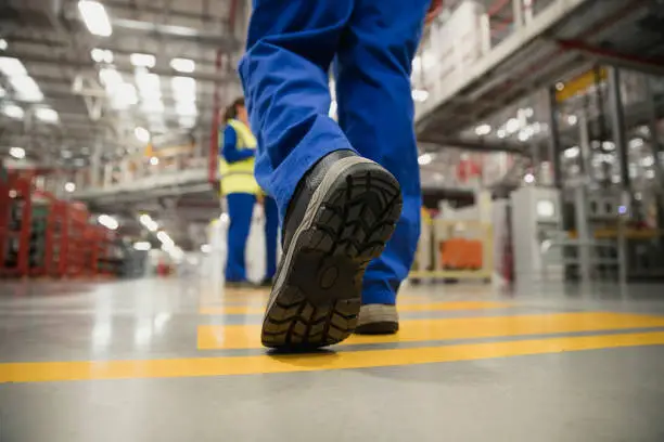 Close-up shot of a workers boot as they walk across the factory floor.