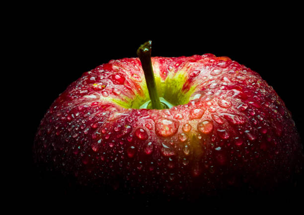 istock Water droplet on glossy surface of red apple on black background 858568372