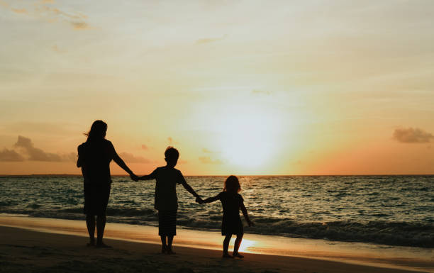 istock mother with three kids walking on beach at sunset 858568792
