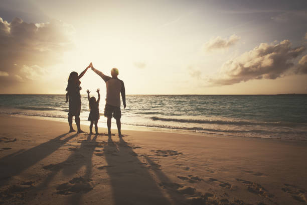 szczęśliwa rodzina z dziećmi bawi się na plaży o zachodzie słońca - enjoyment people beach sun protection zdjęcia i obrazy z banku zdjęć
