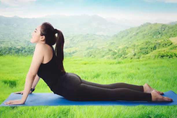 Picture of pretty woman wearing sportswear while practicing yoga in the meadow