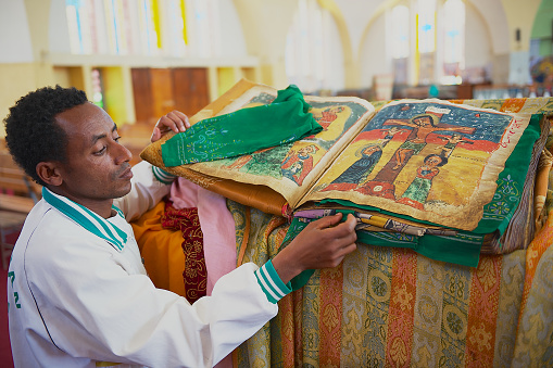 Aksum, Ethiopia - January 25, 2010: Unidentified man demonstrates ancient Bible in Amharic language in the church of Our Lady Mary of Zion, the most sacred place for all Orthodox Ethiopians in Aksum, Ethiopia.