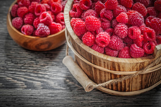 istock Bowl and bucket with raspberries on wooden board 858580474