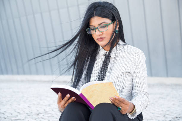 istock Modern intelligent student reading book outdoors 858587768