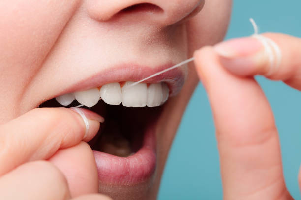 vista lateral cara sonriente mujer con seda dental. - dientes humanos fotografías e imágenes de stock