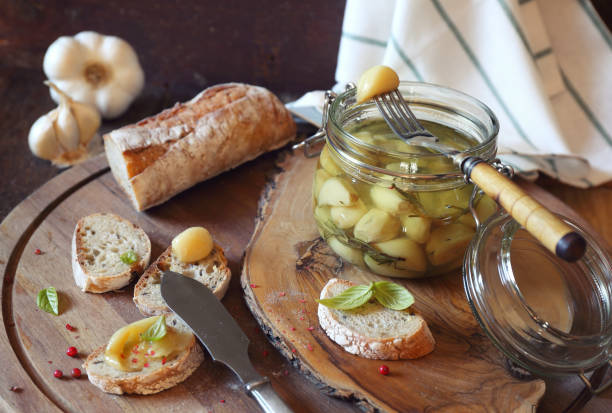 Garlic confit and spread bread Appetizer: garlic confit in jar and french spread bread confit stock pictures, royalty-free photos & images