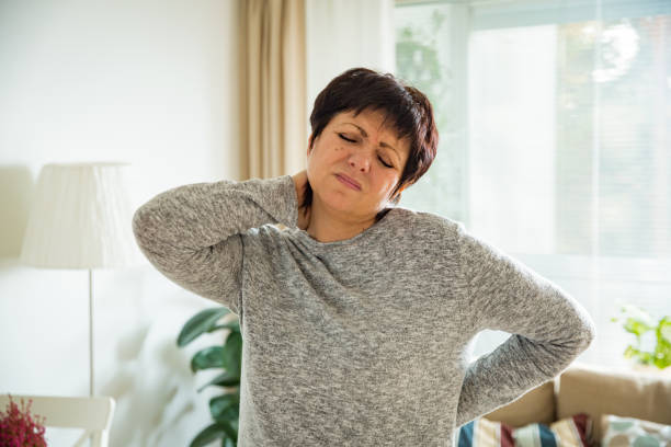 mujer madura sufren de dolor de espalda en casa - pain pressure fotografías e imágenes de stock