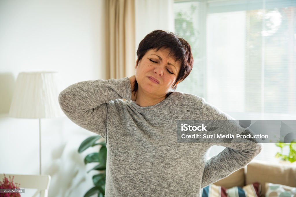 Mature femme souffrant de maux de dos à la maison - Photo de Douleur libre de droits