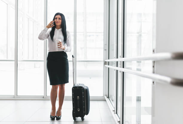 istock Successful business woman with coffee and suitcase in an office setting 858598584