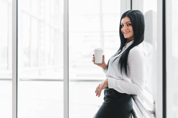 istock Successful business woman with coffee in an office setting 858599362