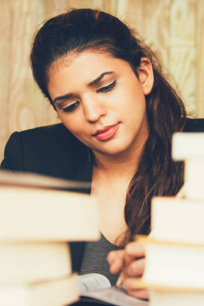 istock Serious female student writing among textbooks 858600608