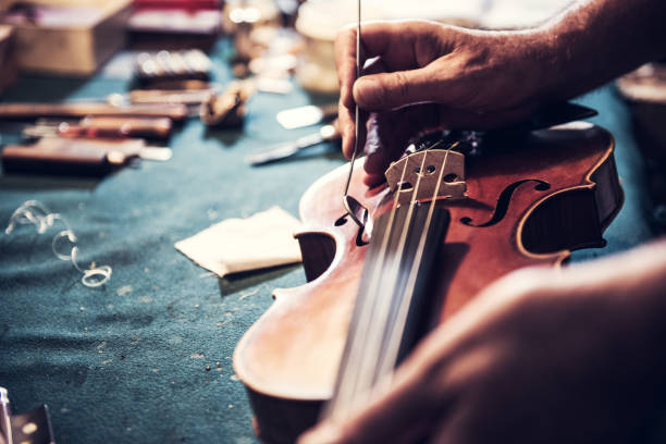 artesano principal comprobar el violín en su taller - fabricante de instrumentos fotografías e imágenes de stock