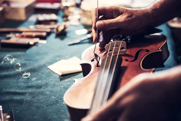 Photo of Senior craftsman checking the violin in his workshop
