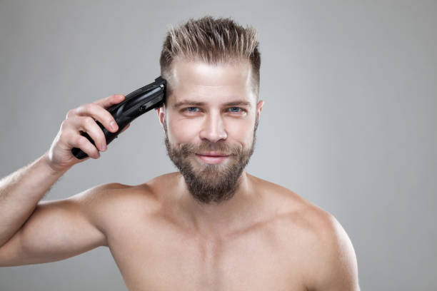 красивый мужчина резки его собственные волосы с клипером - men hairdresser human hair hairstyle стоковые фото и изображения