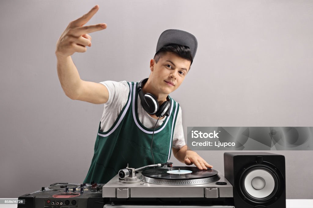 Teenage DJ making a peace sign Teenage DJ making a peace sign against a gray wall DJ Stock Photo