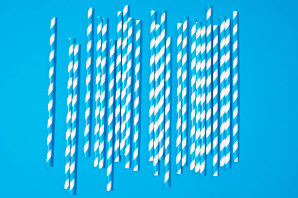 Blue and white striped drinking straws on blue background
