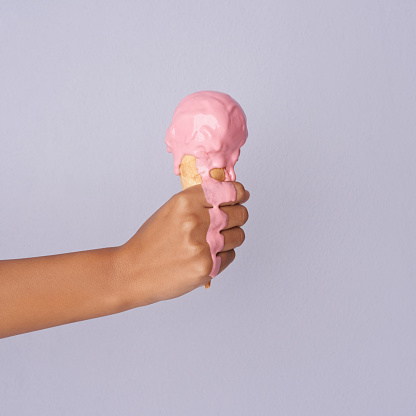 Studio shot of an unrecognizable woman holding a melting ice cream against a purple background