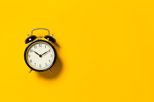 Retro alarm clock on yellow color background