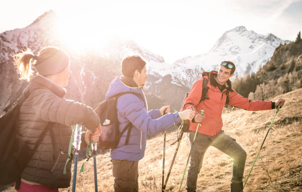 Group of friends trekking on french alps at sunset - Hikers with backpacks and sticks walking on mountain - Wanderlust travel concept with young people at excursion in wild nature - Focus on right guy Group of friends trekking on french alps at sunset - Hikers with backpacks and sticks walking on mountain - Wanderlust travel concept with young people at excursion in wild nature - Focus on right guy base camp photos stock pictures, royalty-free photos & images